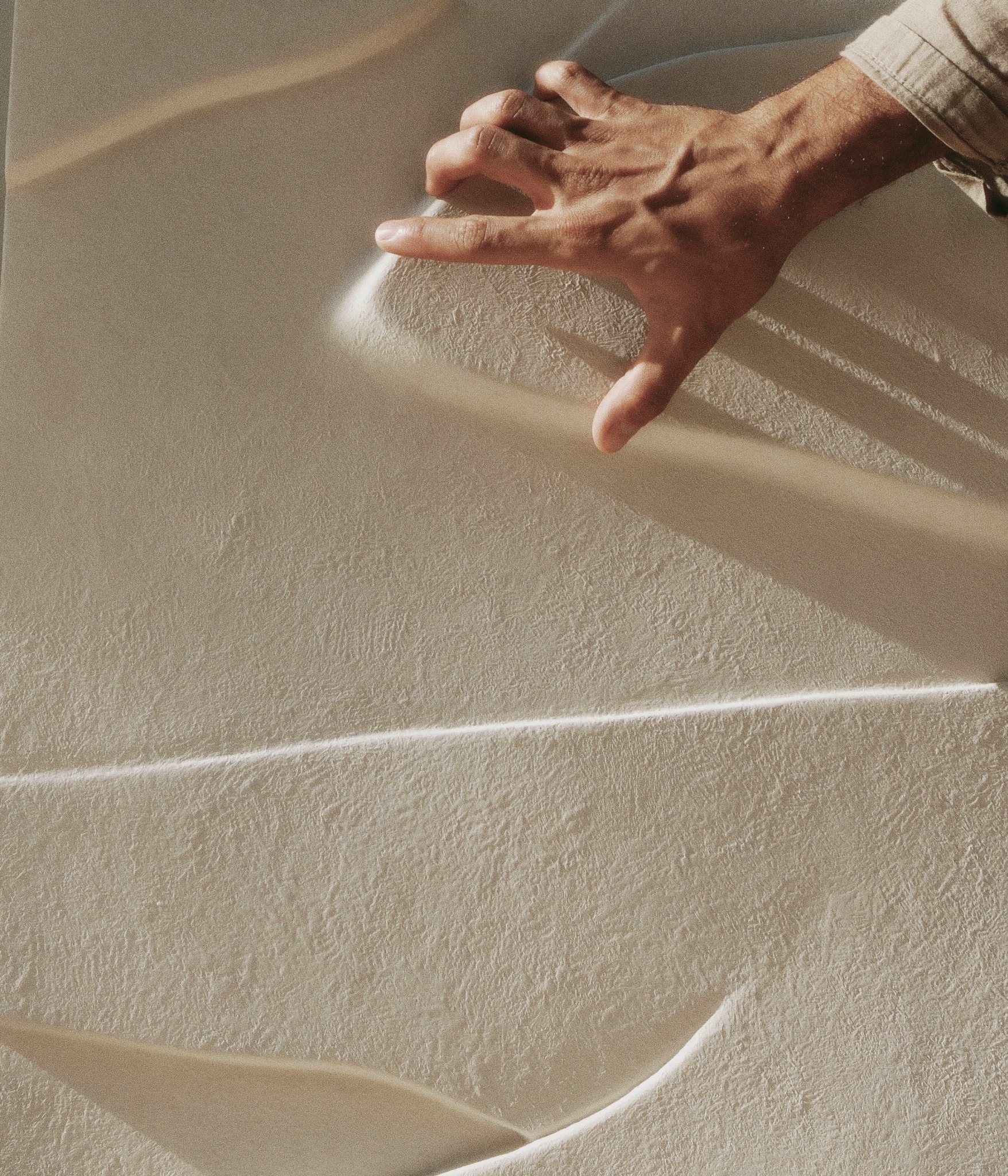 A hand tracing the softly lit surface of an ivory bas-relief.